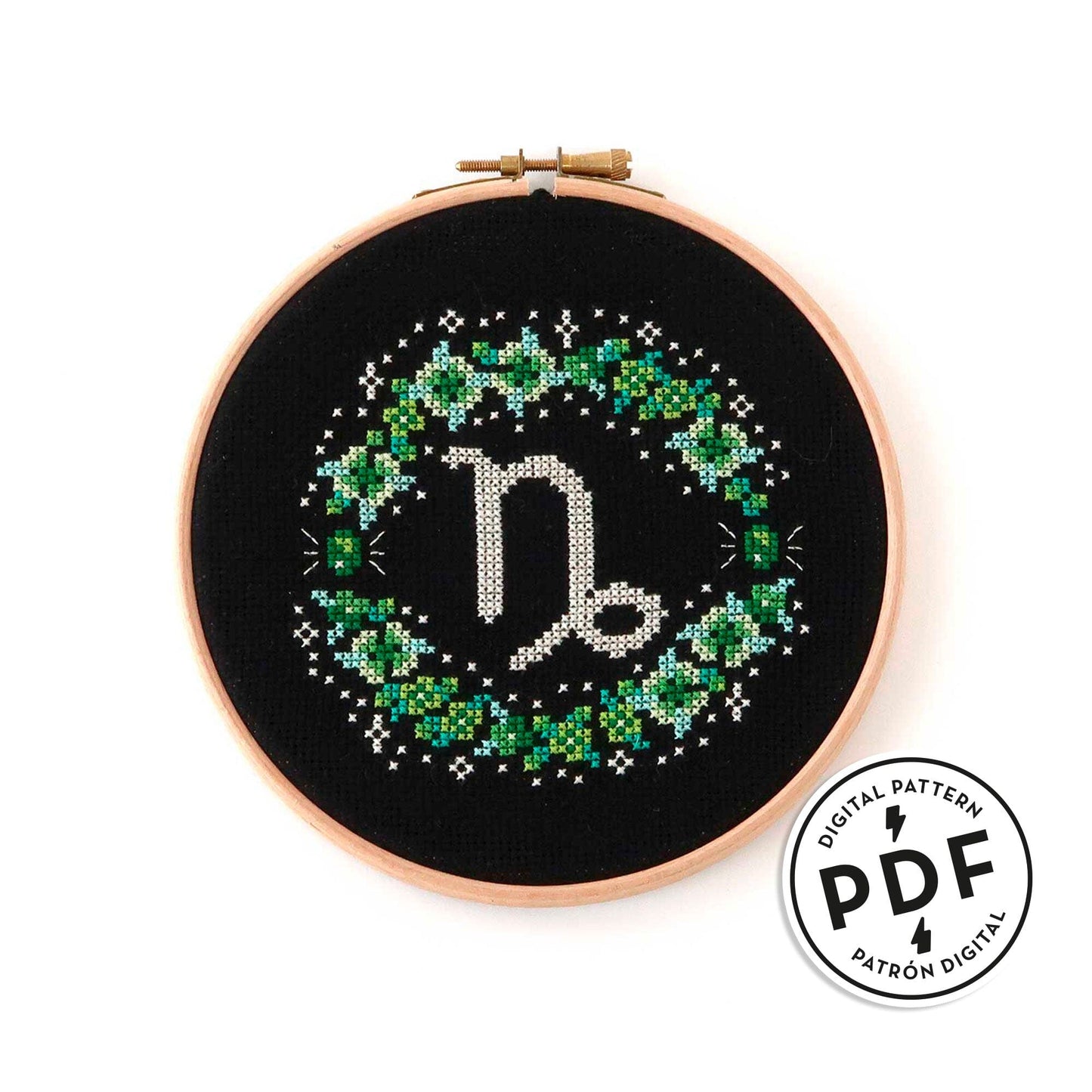 Patrón de punto de cruz en PDF con el signo de Capricornio rodeado de flores en tonos de verde. Signo del zodíaco de punto de cruz moderno y redondo para enmarcar en aro de bordar.