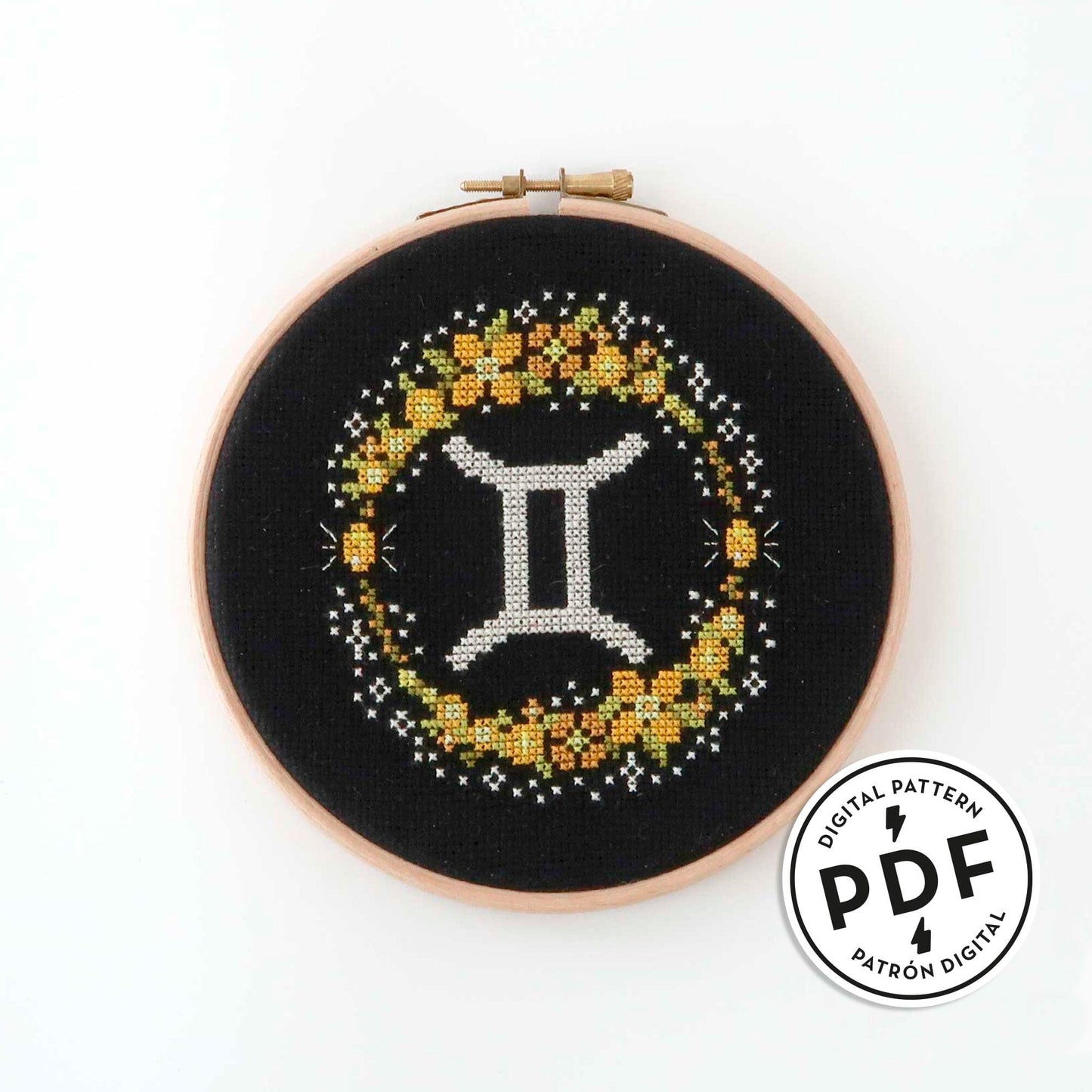Patrón de punto de cruz en PDF con el signo de Géminis rodeado de flores en tonos de amarillo. Signo del zodíaco de punto de cruz moderno y redondo para enmarcar en aro de bordar.