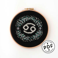 Patrón de punto de cruz en PDF con el signo de Cáncer rodeado de flores en tonos de gris. Signo del zodíaco de punto de cruz moderno y redondo para enmarcar en aro de bordar.