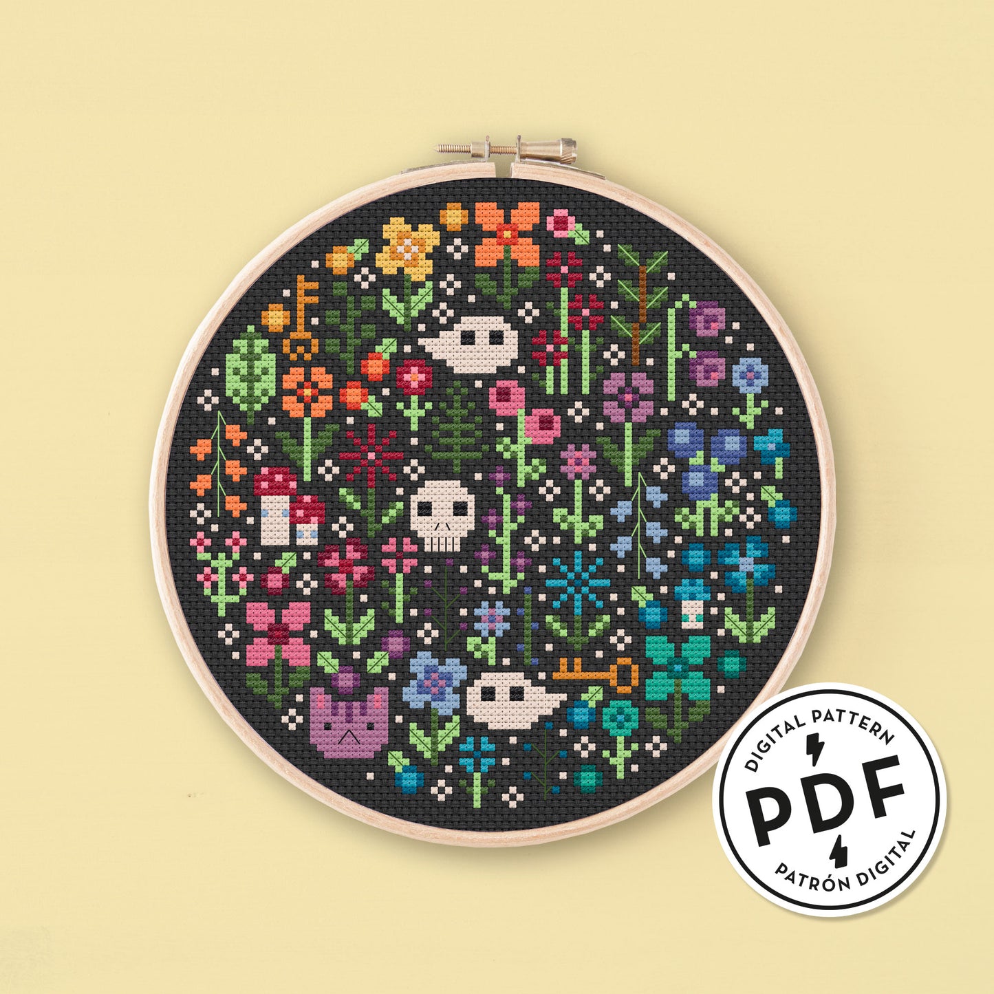 Muestra del Esquema de Punto de Cruz en PDF Mini Rainbow Garden. Bordado redondo de flores de colores del arcoiris, gatos, calaveras, fantasmas, setas y llaves. Punto de cruz sobre tela negra.